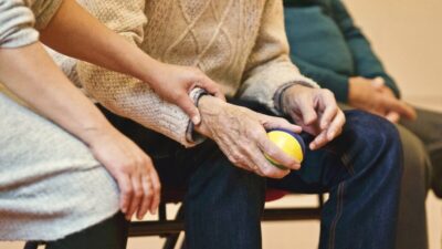 an elderly person holding a ball, helped by a younger person