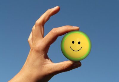 A hand holding a yellow smiley face