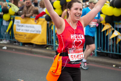 Helen, a BHF London Marathon runner in 2021, raises her arms in salute.