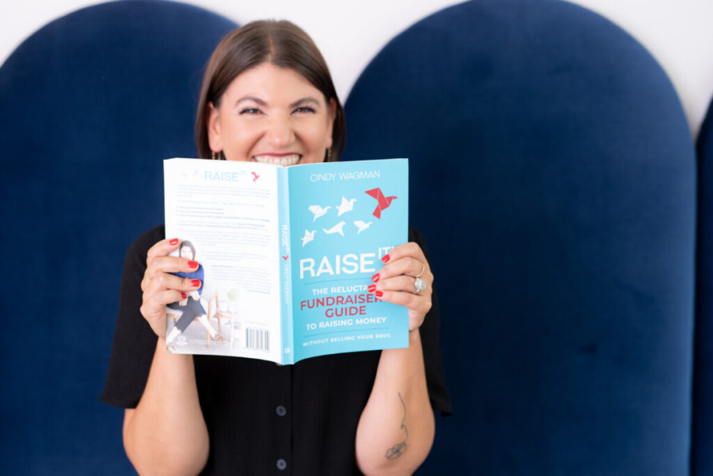 Cindy Wagman smiling as she holds her new book Raise It