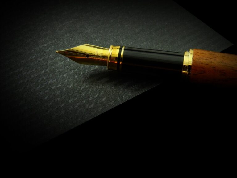 A fountain pen with a gold nib against a black background