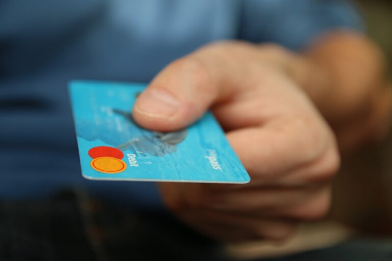 A man's hand holding out a debit card