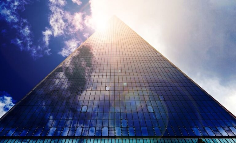 a skyscraper reaching up into a blue and cloudy sky