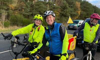 Matt Baker & Millie in cycling helmets and jackets on the rickshaw as part of the rickshaw challenge for BBC Children in Need