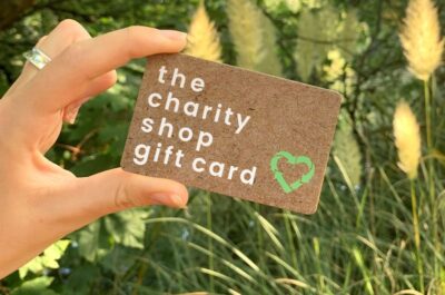 TA hand holds a Charity Shop Gift Card