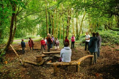 People sitting and standing in a circle in a wood. Photo: Co-op Foundation