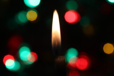 A candle flame against green and red lights on a dark background