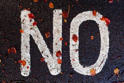 The word no, painted in white on a road with autumn leaves