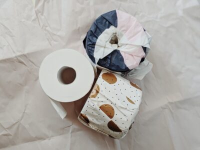 Three toilet rolls. Two are wrapped in pretty patterned paper, like a gift