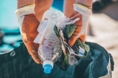 A volunteer puts a handful of plastic litter into a bag at the beach
