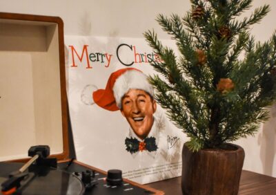 A Christmas record sits next to a record player, behind a small christmas tree
