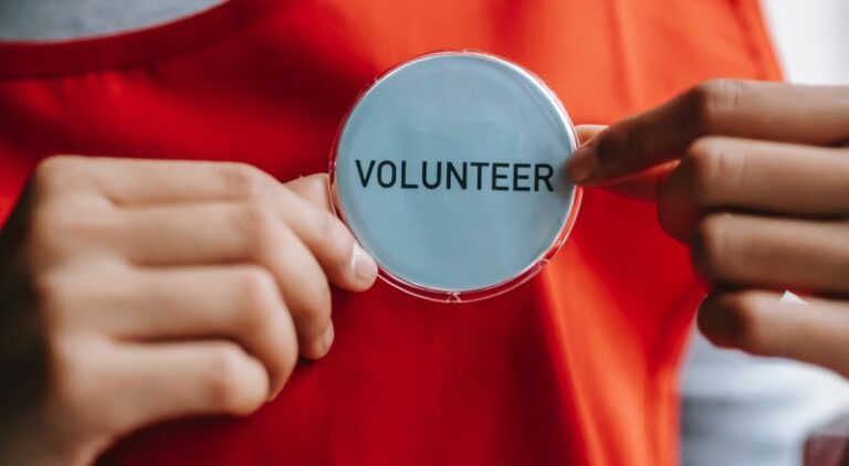 hands hold a volunteer badge on an orange top