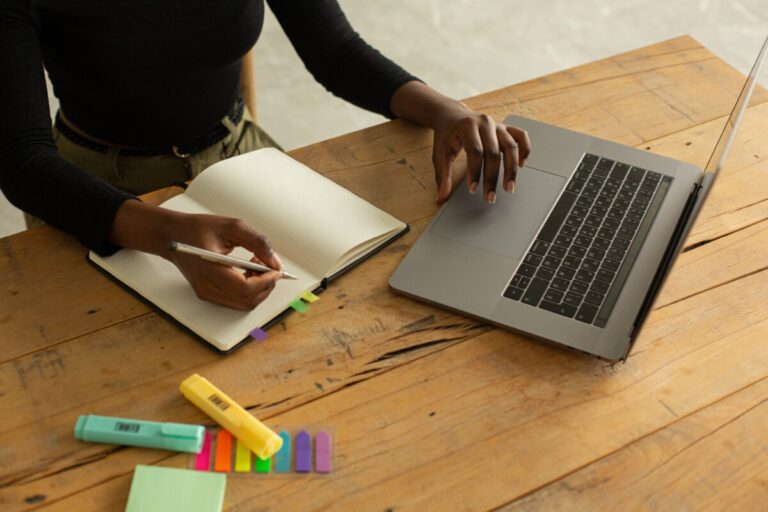 A woman surfing the internet and writing in a notebook