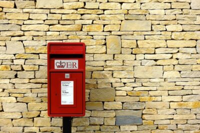 a red post box against a dry stone wall