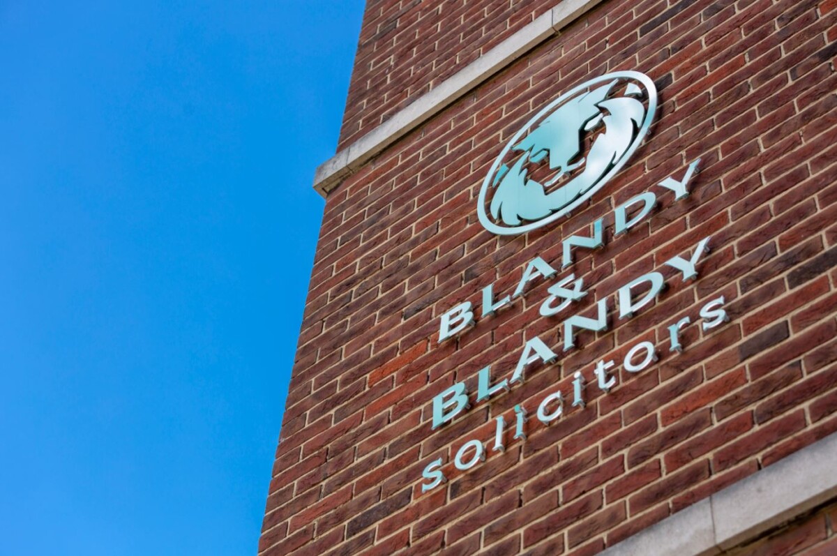 A brick wall against a blue sky with the name and logo of Blandy & Blandy Solicitors