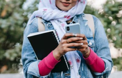 A woman in a headscarf looks down at her phone