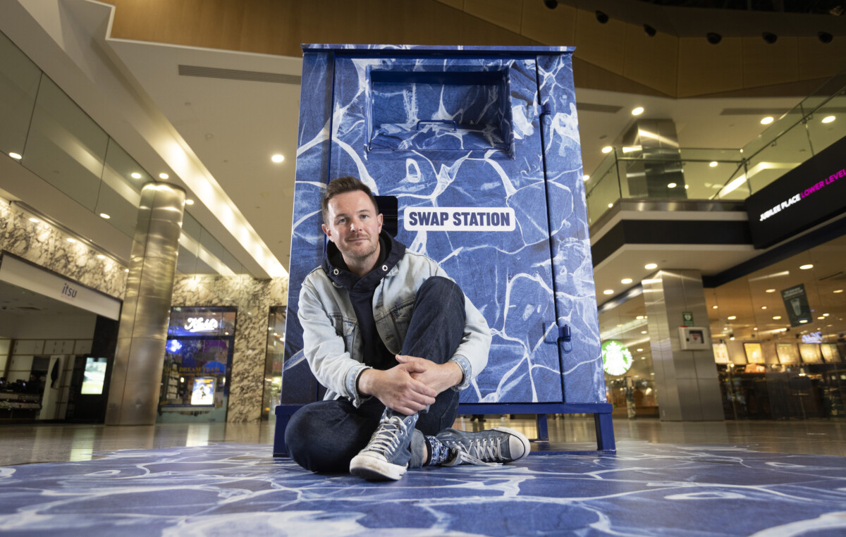 Artist Ian Berry sits in front of the Swap Station in Canary Wharf, where people can donate unwanted clothing in return for shopping vouchers