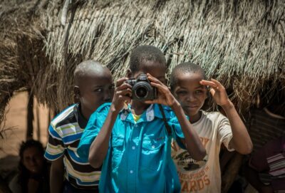 Children in a Mozambique village aim a camera at the photographer. By Martin Bekerman on Unsplash