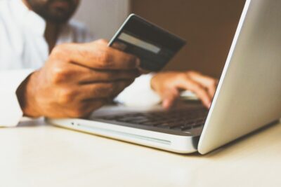 Shopping. A man's hand holding a credit card in front of his laptop