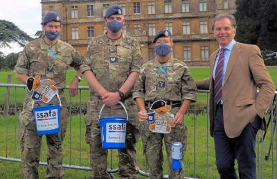 Soldiers hold donation buckets and QR codes for SSAFA