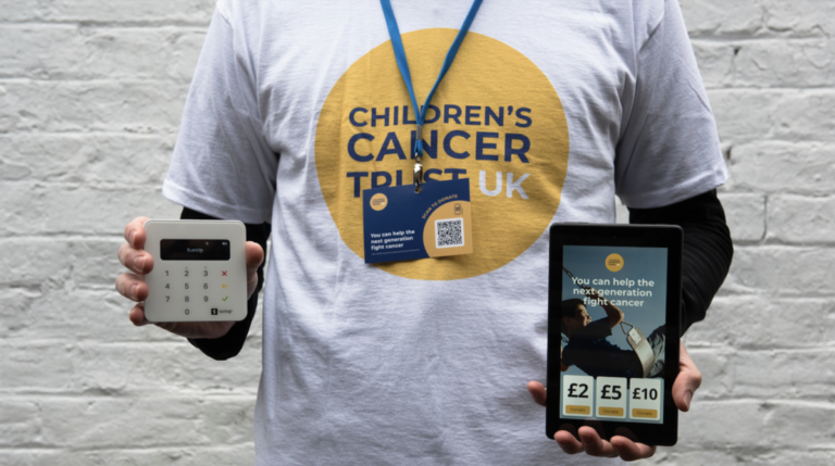 A fundraiser wearing a Children's Cancer Trust UK t-shirt holds different cashless donation options