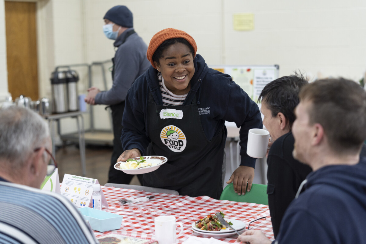 FoodCycle volunteer Bianca chats to people eating a meal