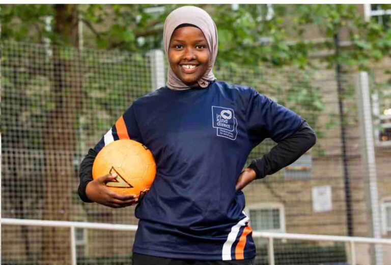 Football referee Jawahir Roble smiles at the camera with an orange football under her arm