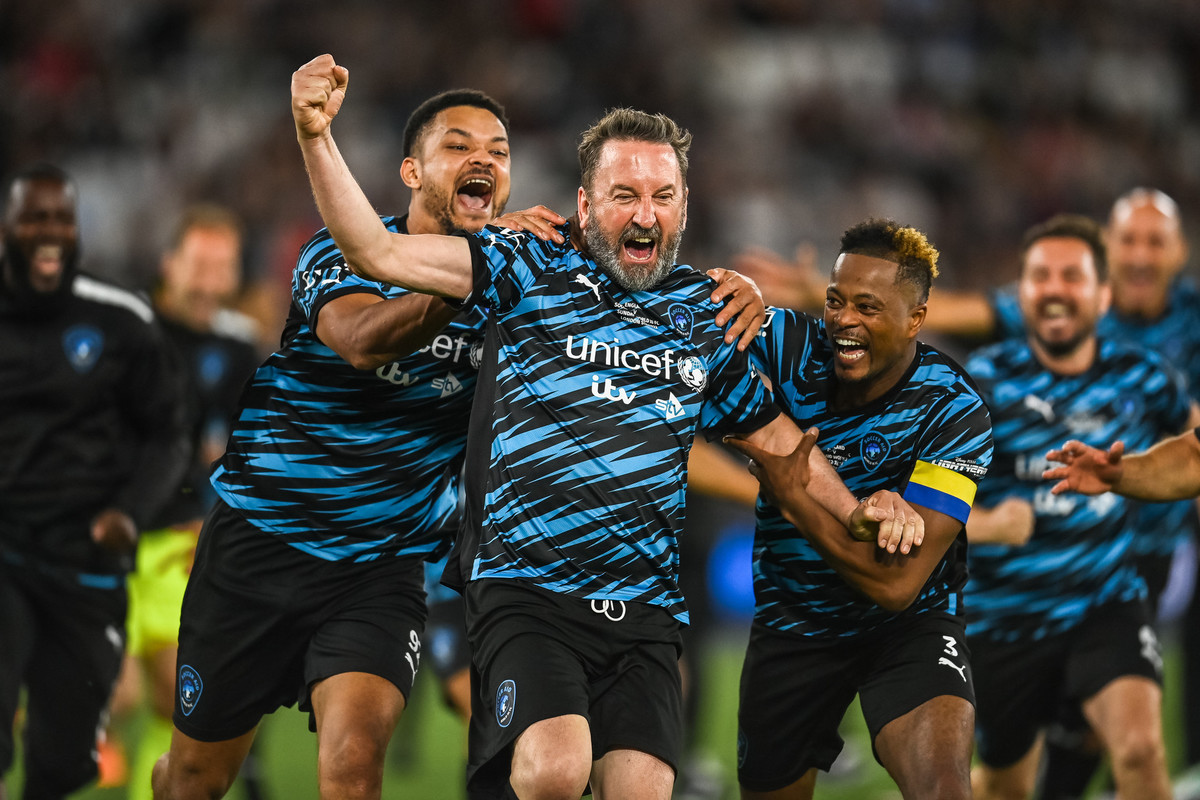Lee Mack of World XI is mobbed by Steven Bartlett (left) and Patrice Evra (right) after scoring his sides winning penalty kick during Soccer Aid for UNICEF 2022 taking place on Sunday 12th June at the London Stadium, Stratford