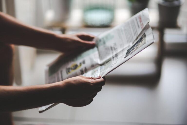 Arms holding out a newspaper to read. By Karolina Grabowska on Pixabay