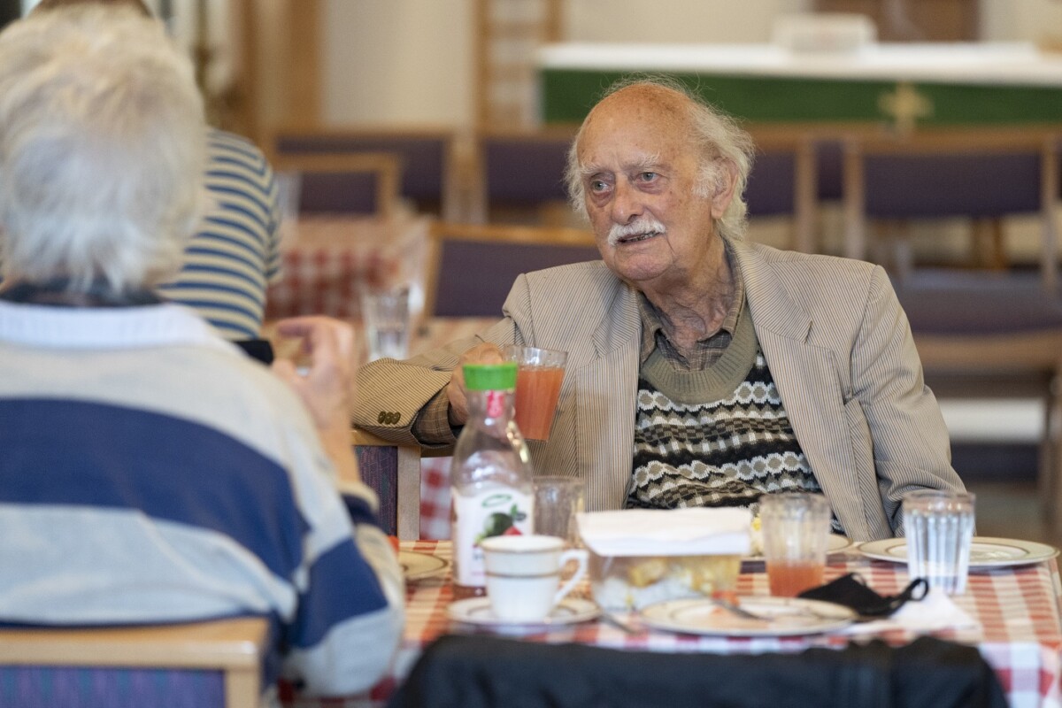 Man sits at a table eating and drinking at FoodCycle, Kilburn. Photo: City Bridge Trust