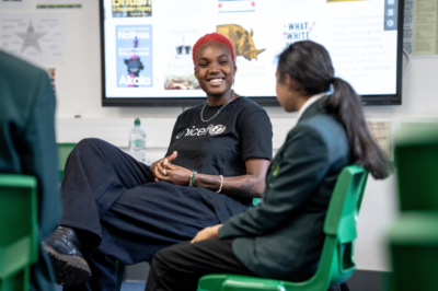 Arlo Parks talks to a student in a classroom as part of her role as a UNICEF UK High Profile Supporter