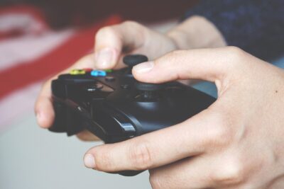 hands holding a gaming console. By Anton Porsche on Pexels