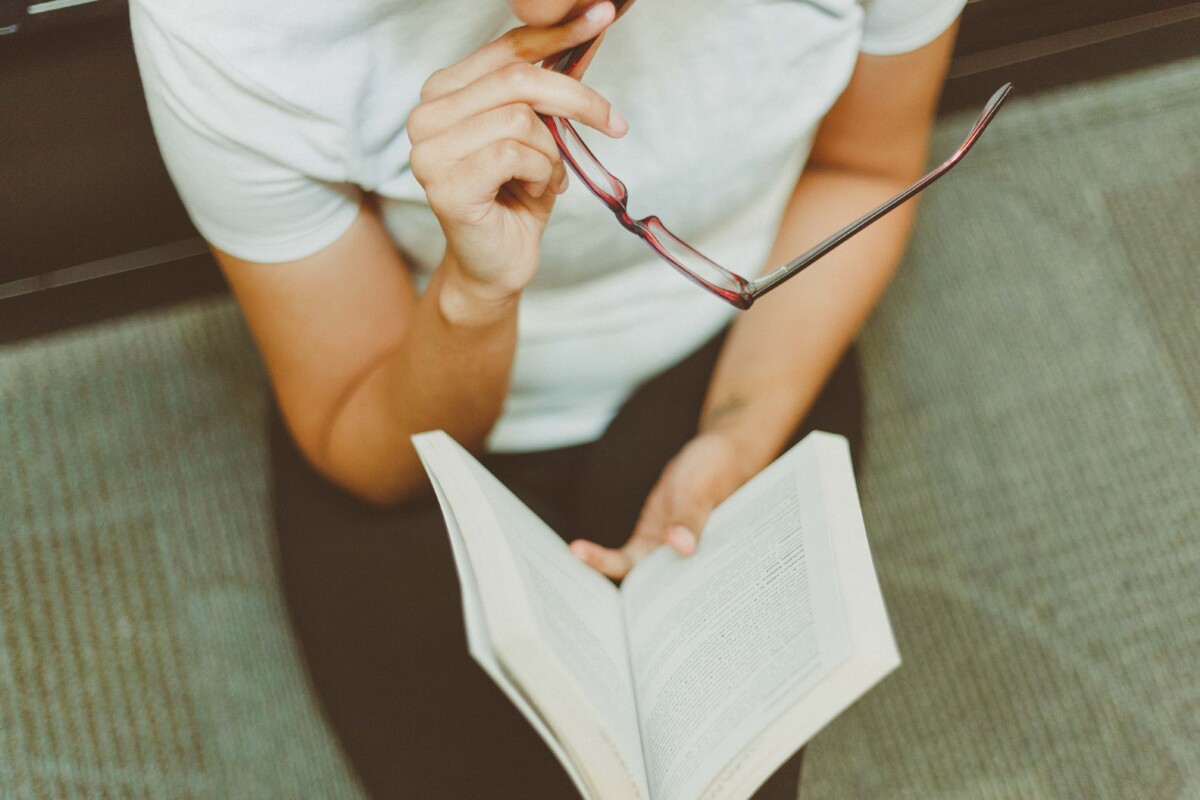 Looking down on a woman reading a book. Photo by Julia Avamotive on Pexels