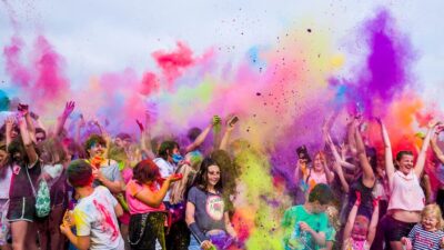People participate in a colour run surrounded by clouds of coloured paint dust
