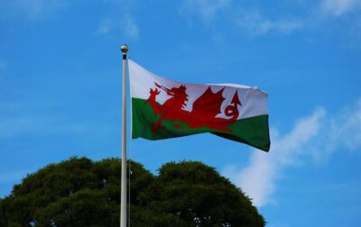 The Welsh flag flutters in the breeze against a blue sky. By Dean Moriarty from Pixabay