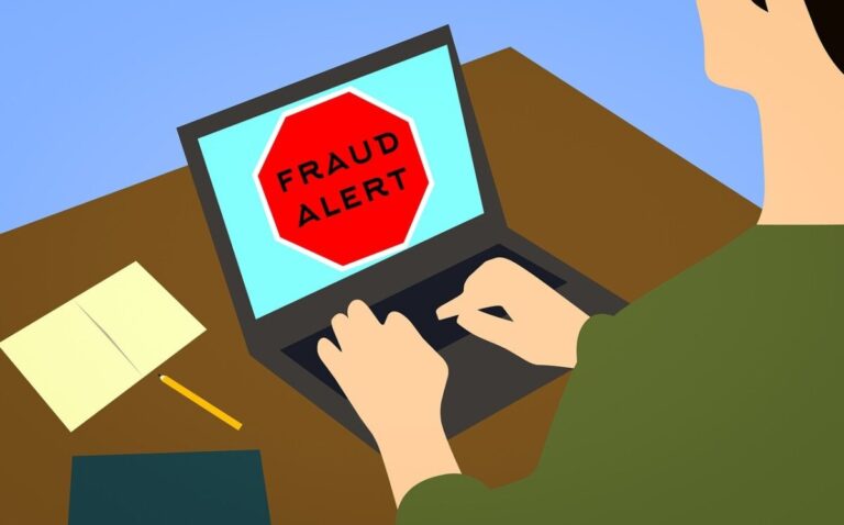 An illustration of a person at a laptop that has a fraud alert on the screen, by Mohamed Hassan on Pixabay
