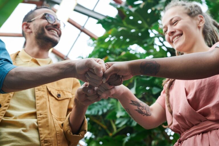a group of smiling people fist bump. By Fauxels on pexels
