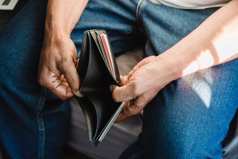 A man looks into his empty wallet. By Nicola Barts on Pexels