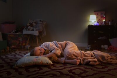 A young girl sleeps on the floor in a room without a bed. A still from Aberlour's new fundraising TV advert.