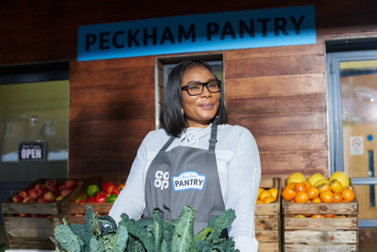 A woman holds a box of vegetables outside Peckham Pantry as part of Co-op's Christmas campaign