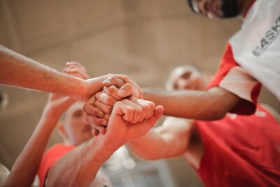 a basketball team stack hands. By Andrea Piacquadio on Pexels