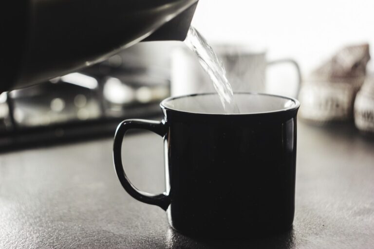 A black kettle pours hot water into a black mug. By Abbat1 on Pixabay