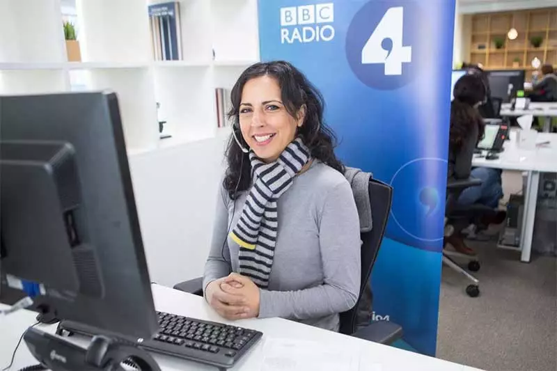 Woman handling BBC Radio 4 donations at a desk with a PC, in front of a BBC Radio 4 pop-up banner. Photo: BBC