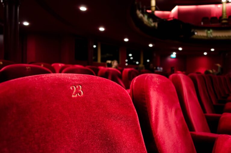 A row of red seats in a cinema or theatre. By Kilyan Sockalingum on Unsplash