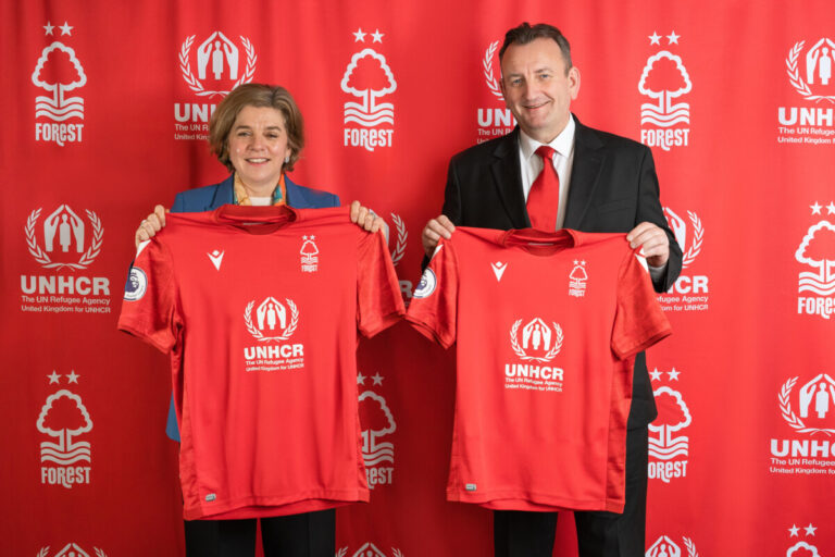 Charlotte Boyle (UNHCR) and Evangelos Marinakis (Nottingham Forest FC) holding up the new charity sponsorship football shirts.