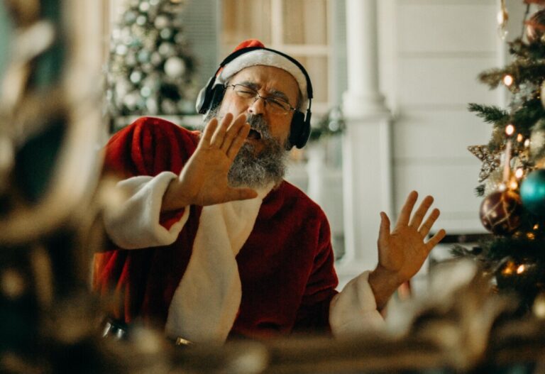 Father Christmas dances with headphones on as he listens to music. By Cottonbro on Pexels