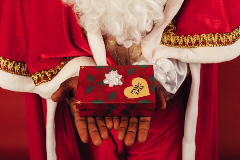 Santa holds out a gift. By Koolshooters on Pexels