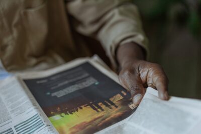 A man's hand holds a newspaper. By Ron Lach on Pexels