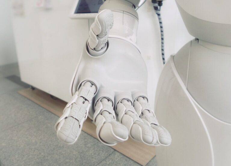 A white robot hand reaches out. By Possessed Photographjy on unsplash