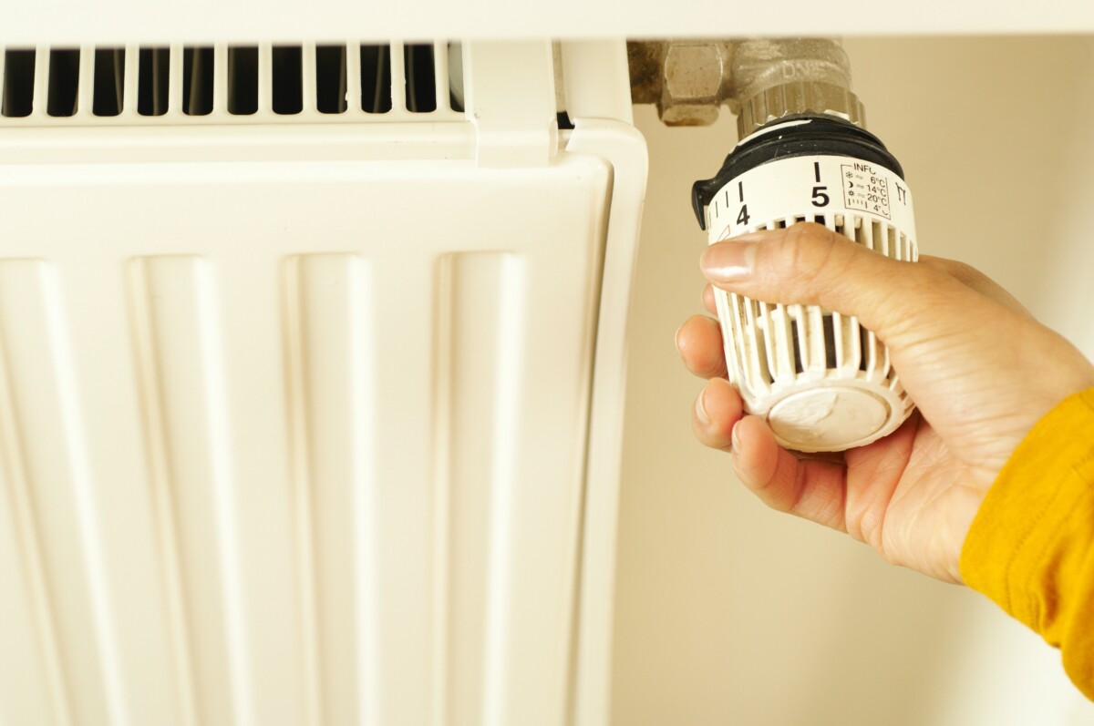 Adjusting the thermostat on a white radiator. Photo: Pexels.com